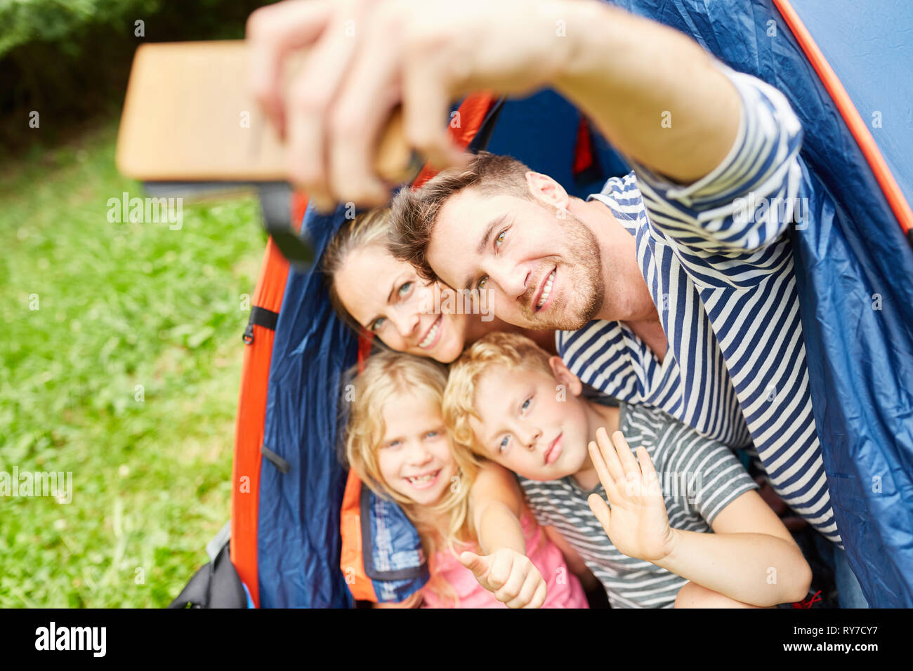 Famiglia con bambini in tenda è tenuto a selfie con lo smartphone in campeggio Foto Stock