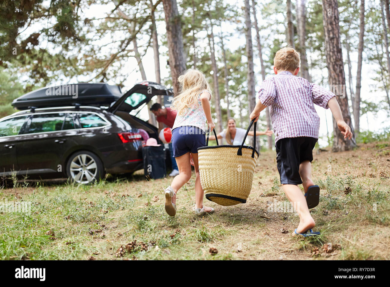 I due ragazzi correre con una sacca per la vettura prima di viaggiare durante le vacanze estive Foto Stock