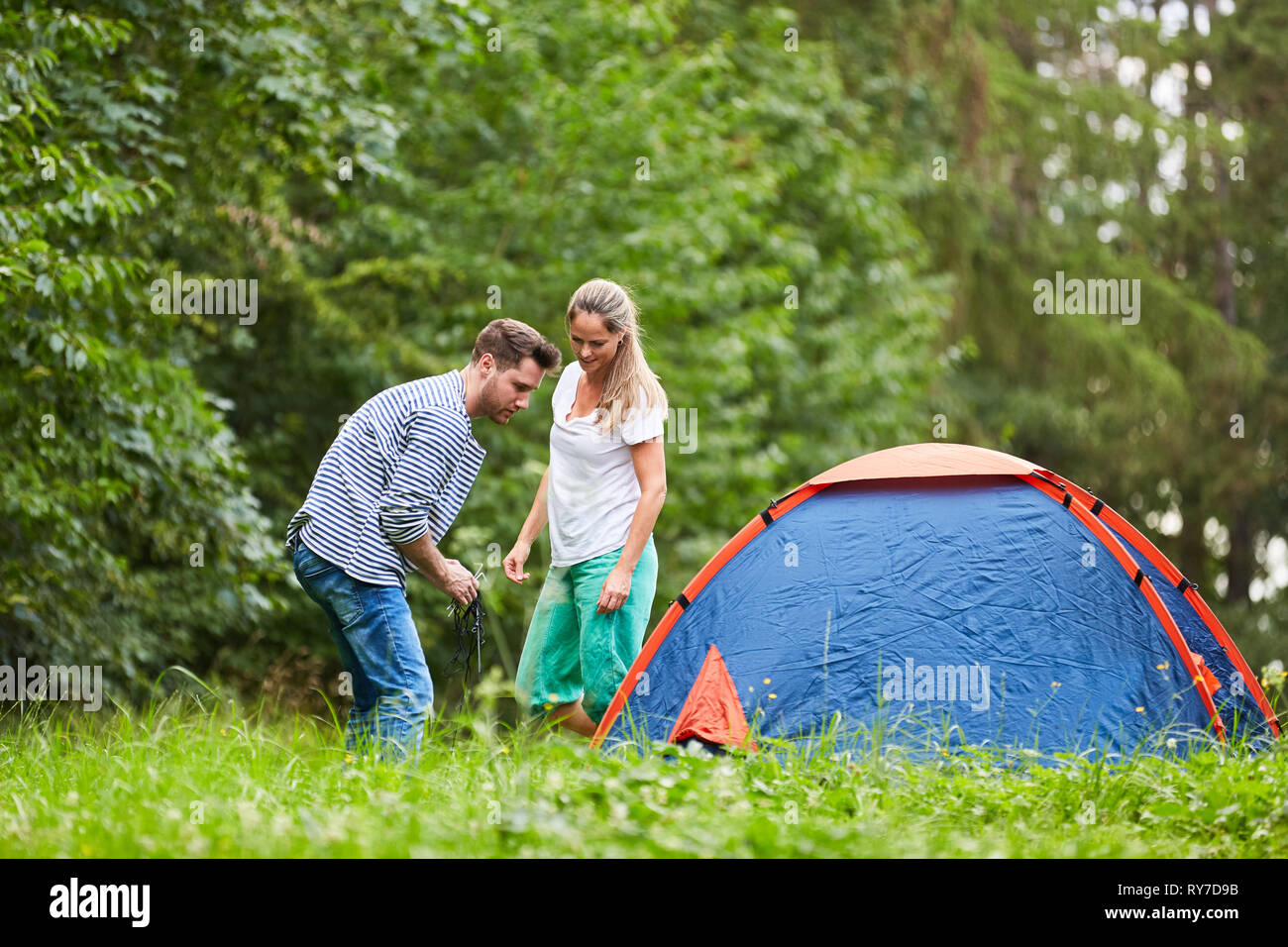 Coppia giovane insieme costruire una tenda in natura in vacanza in campeggio Foto Stock