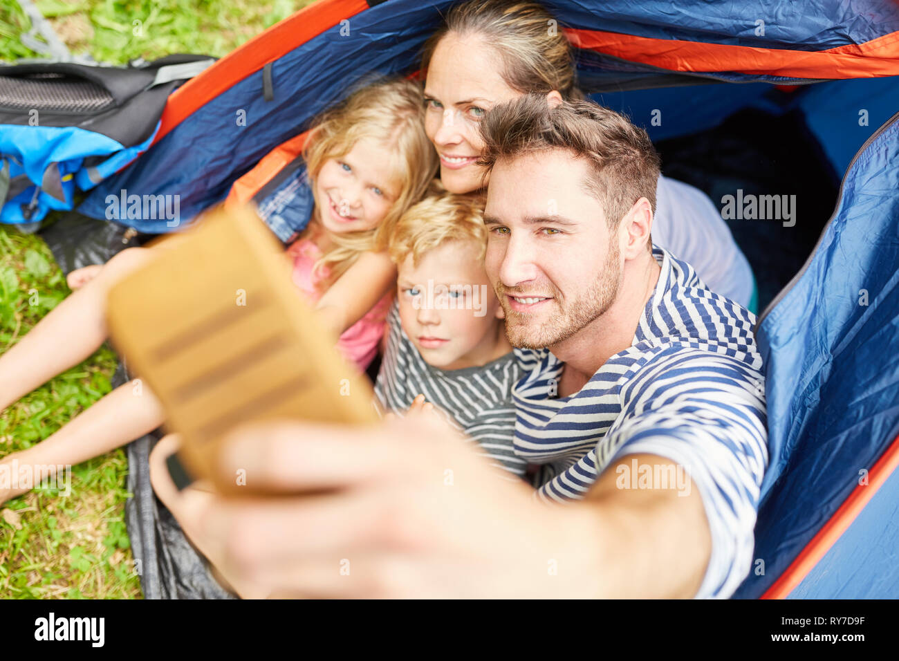 La famiglia felice in vacanza è tenuto un autoritratto con lo smartphone nella tenda Foto Stock