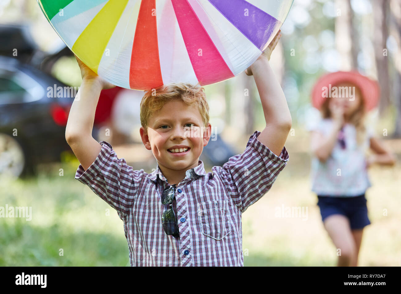 Felice ragazzo giocando con una palla colorata in giardino in estate Foto Stock