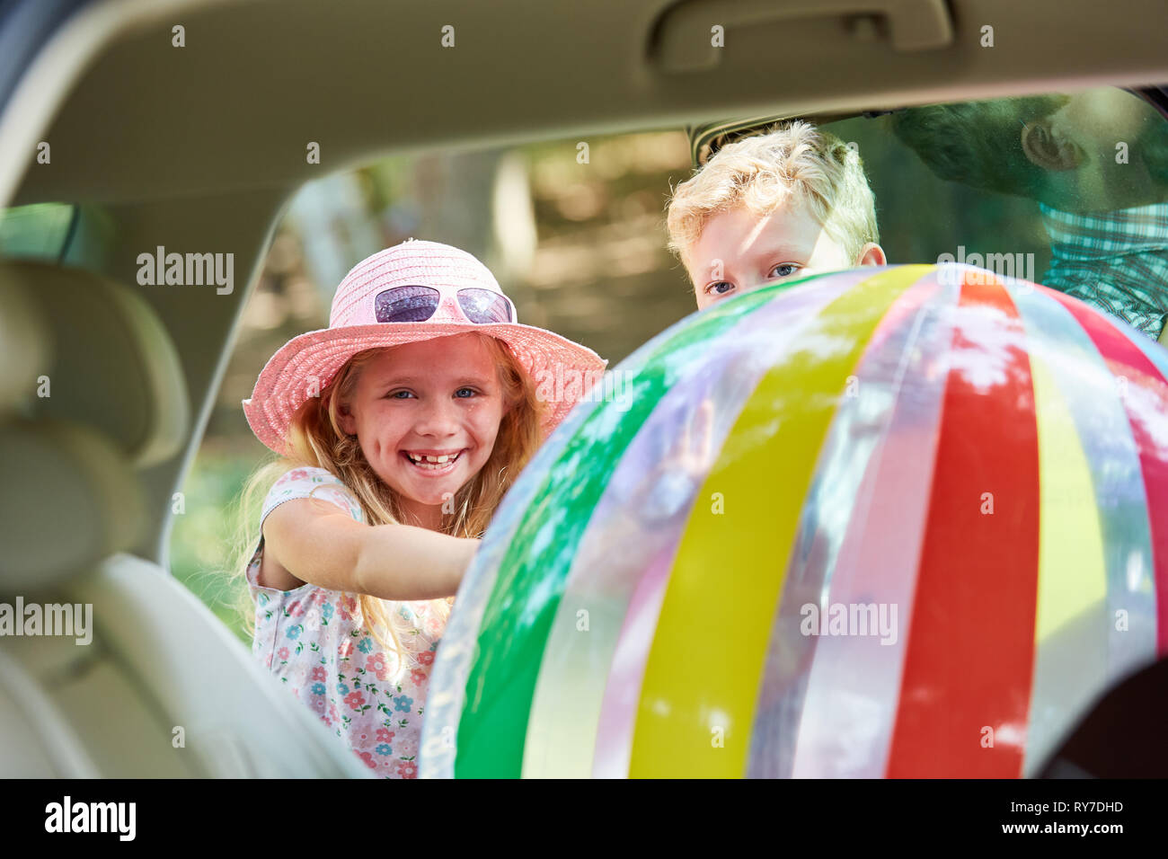 Bambini riporre una grande sfera colorata nel sedile posteriore in auto prima di viaggiare Foto Stock