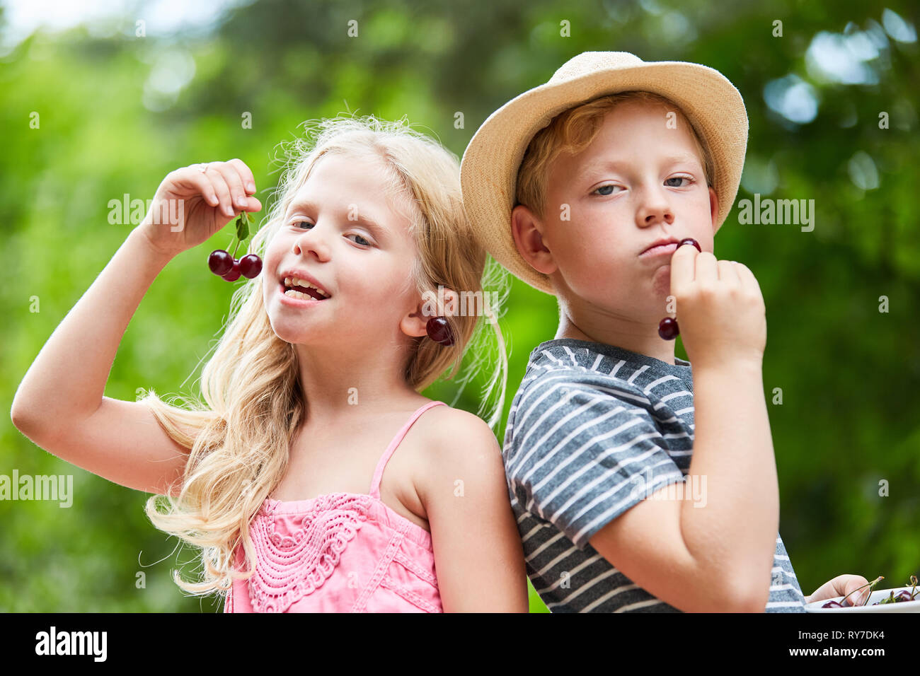 Due bambini come amici o fratelli giovane sgranocchiando le ciliegie insieme Foto Stock