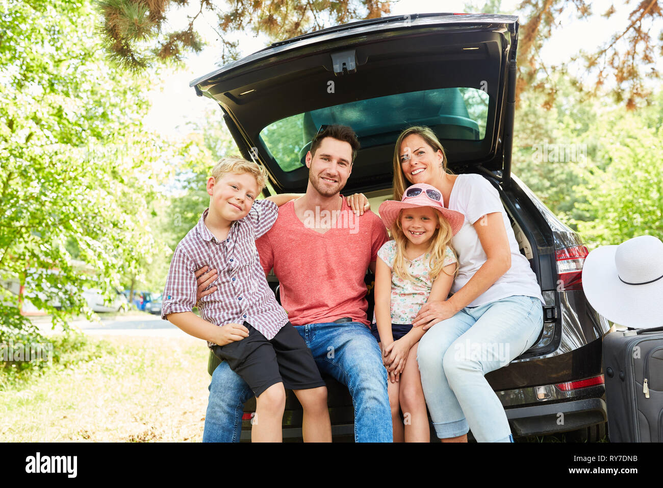 La famiglia felice e i bambini prima di viaggiare in vacanza estiva presso la macchina Foto Stock