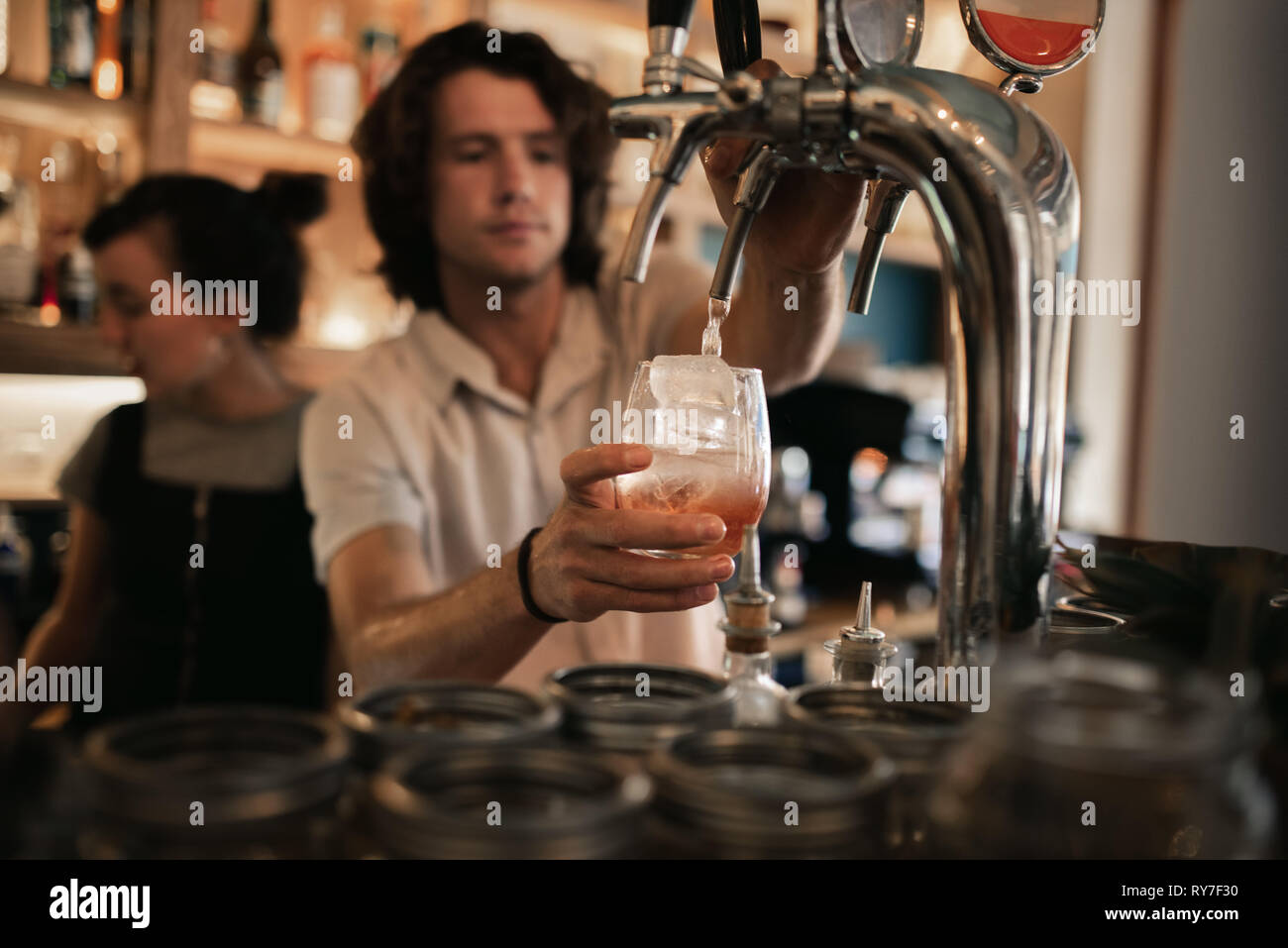 Barista mescolare bevande dietro un banco di bar di notte Foto Stock