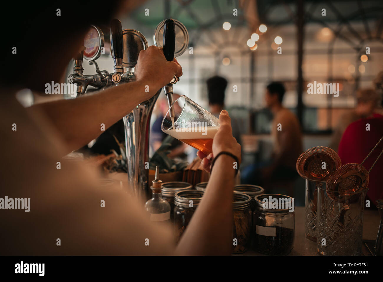 Il barista a versare birra dietro un banco di bar di notte Foto Stock