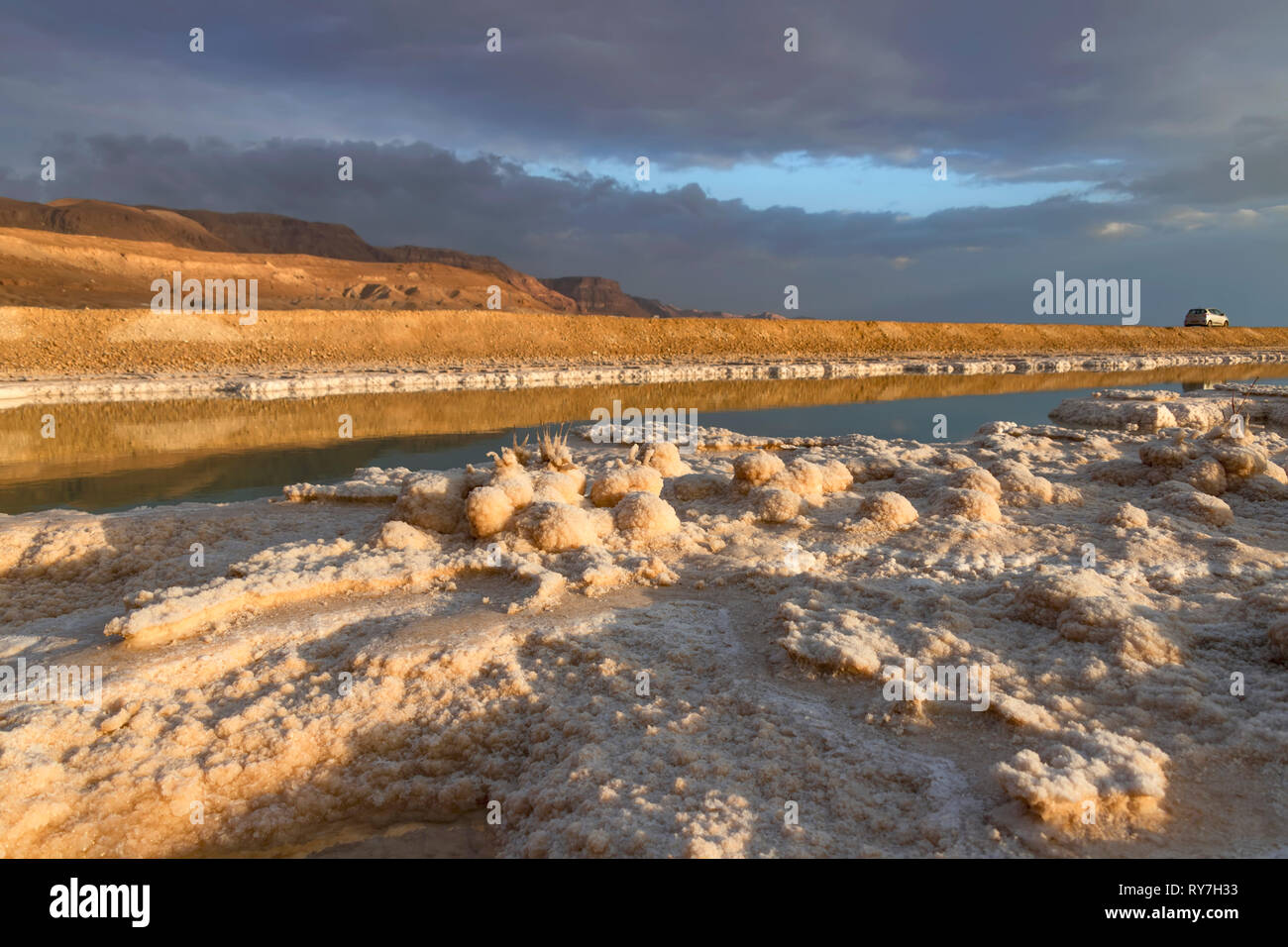 Formazioni di cristalli di sali minerali nelle acque del Mar Morto. Costa con monti all'orizzonte. Seascape Foto Stock