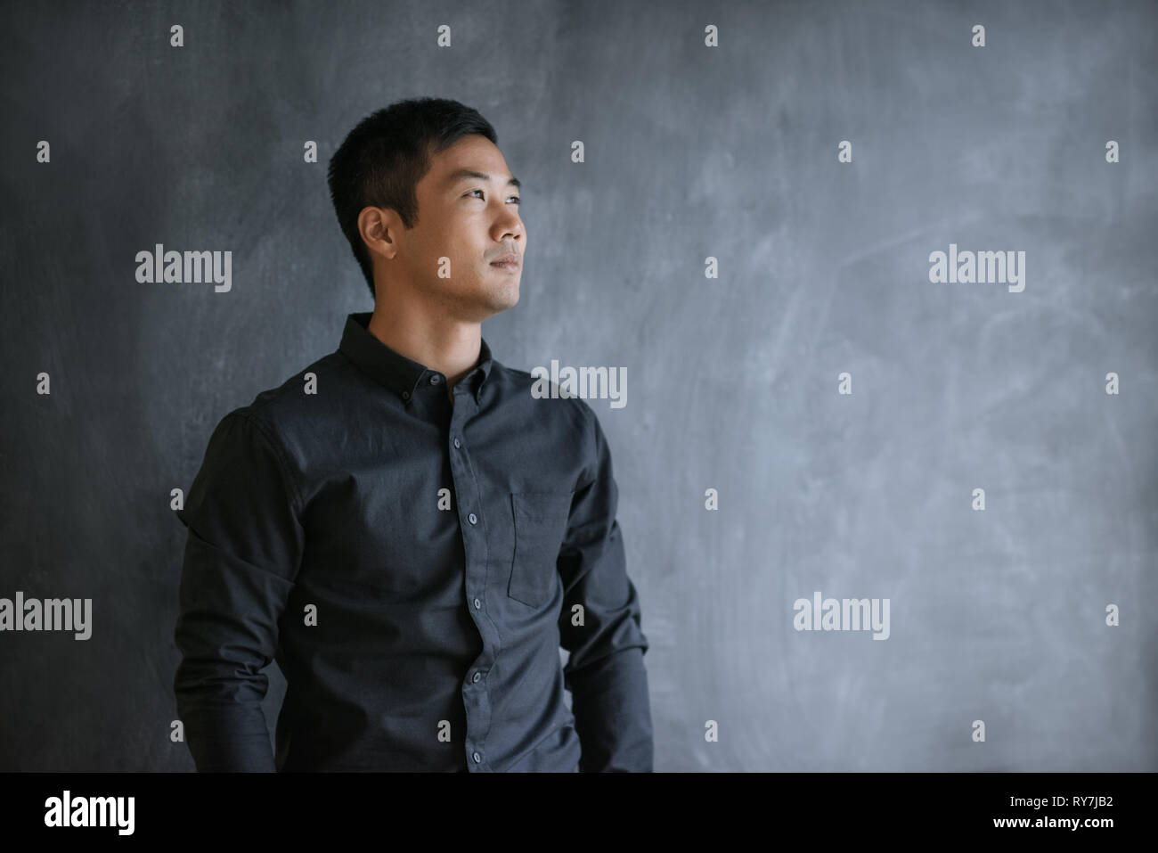 Imprenditore asiatici pensando mentre in piedi di fronte a una lavagna Foto Stock