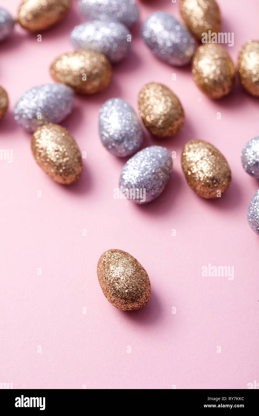 Oro e argento glitter uova di pasqua su un pastello sfondo rosa. Foto Stock