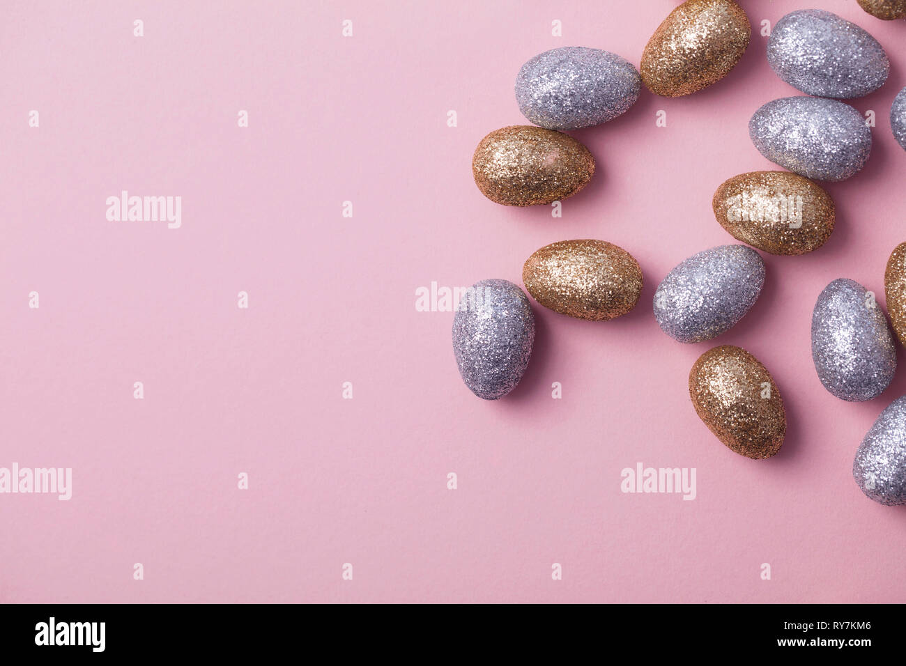 Oro e argento glitter uova di pasqua su un pastello sfondo rosa. Foto Stock