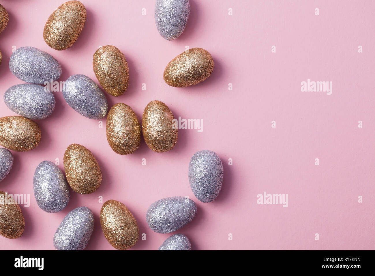 Oro e argento glitter uova di pasqua su un pastello sfondo rosa. Foto Stock