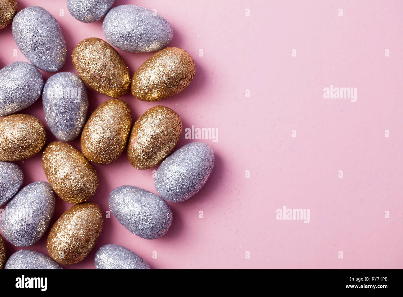 Oro e argento glitter uova di pasqua su un pastello sfondo rosa. Foto Stock