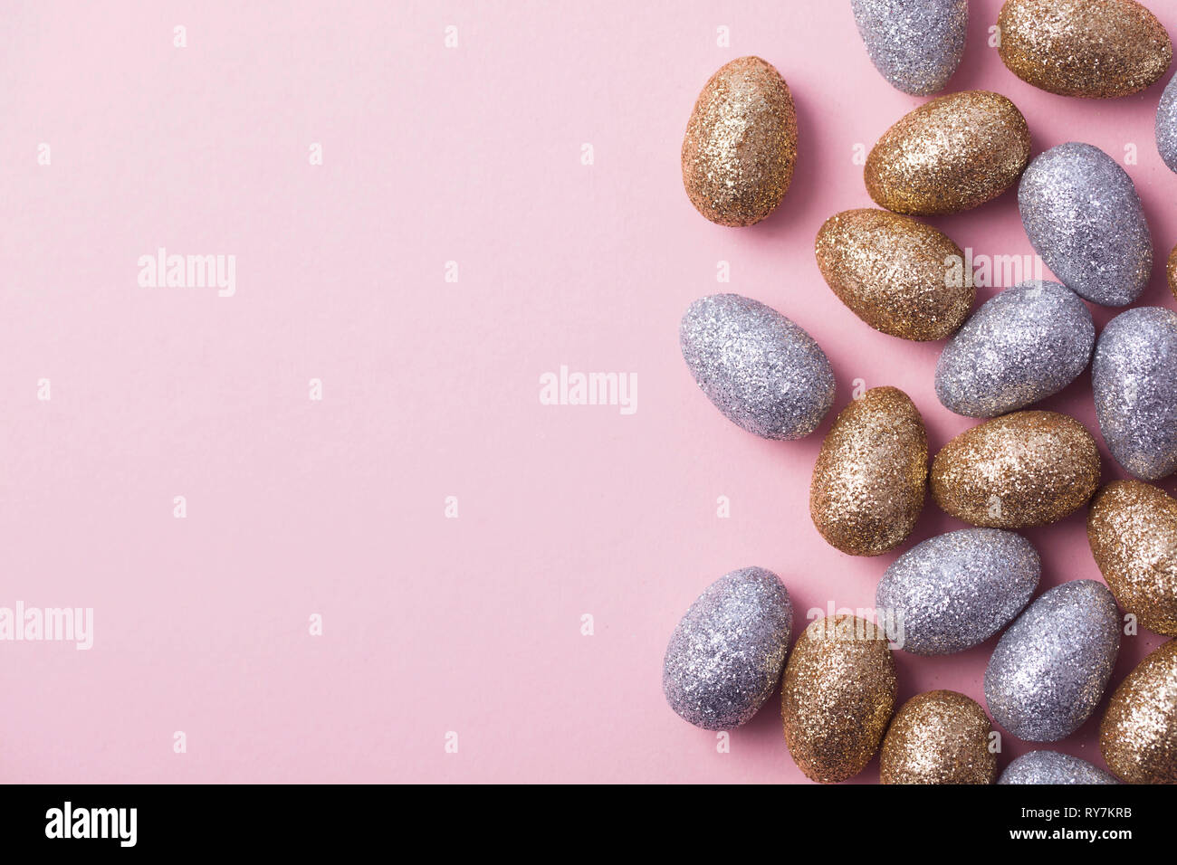 Oro e argento glitter uova di pasqua su un pastello sfondo rosa. Foto Stock