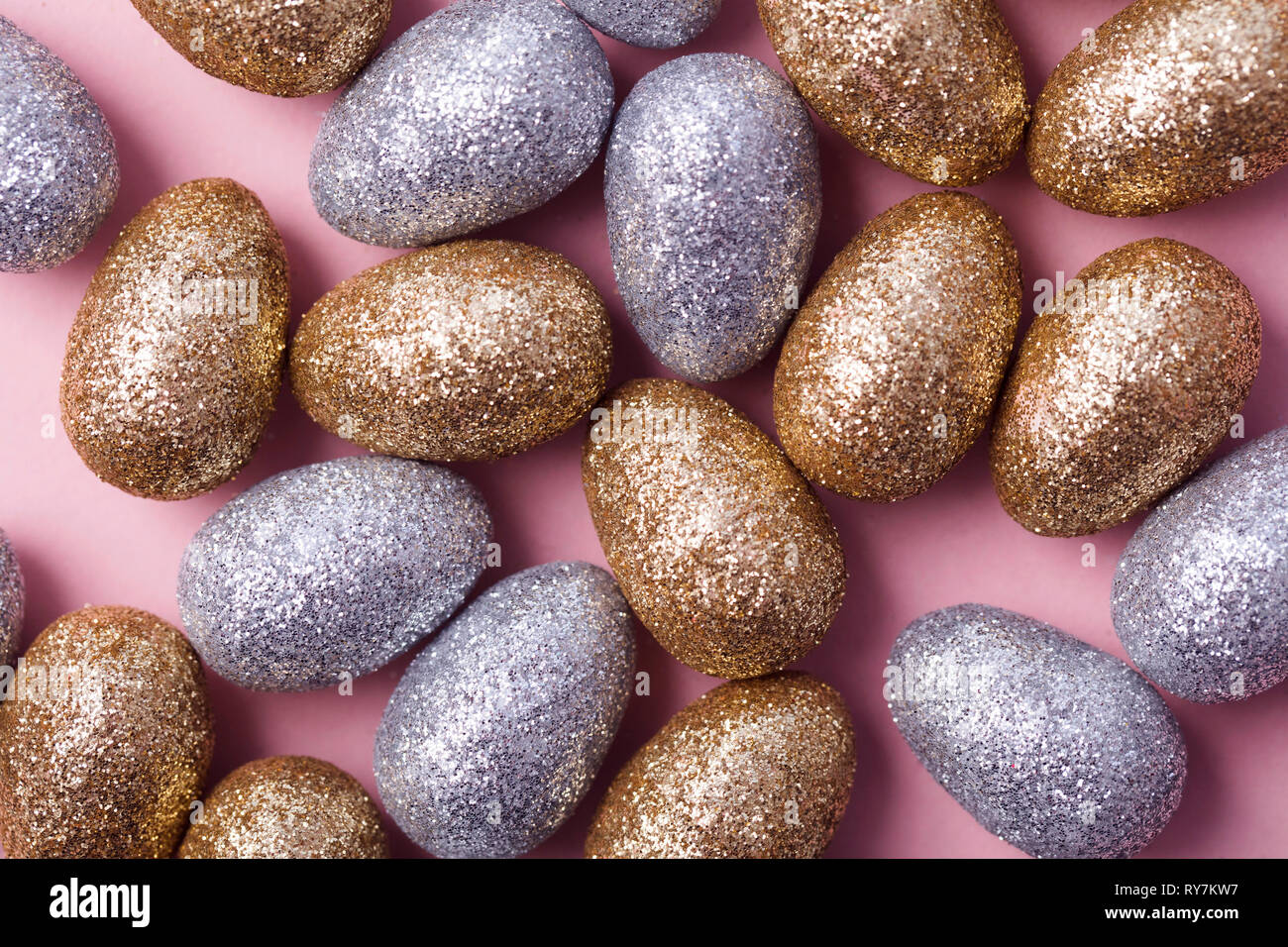 Oro e argento glitter uova di pasqua su un pastello sfondo rosa. Foto Stock