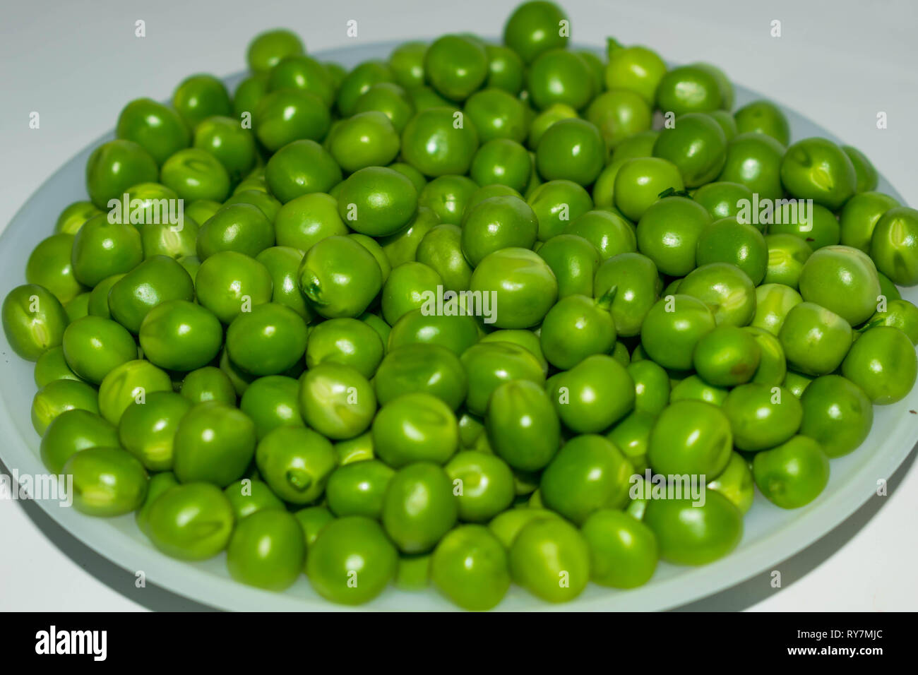 Green pea pod,piselli verdi in una ciotola bianco,sfondo bianco. Foto Stock