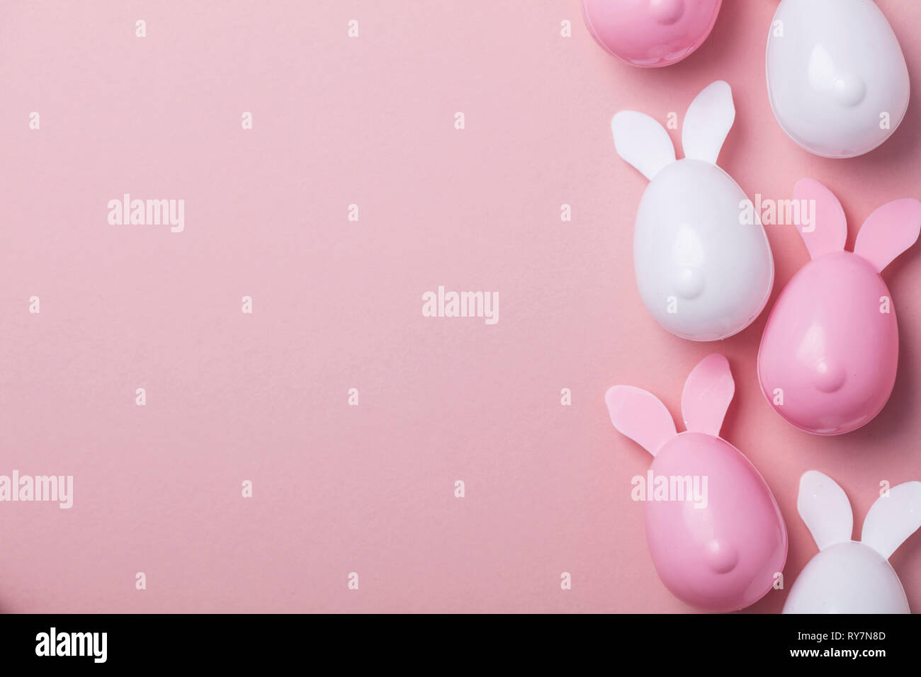 Le uova di pasqua con orecchie di coniglietto su un pastello sfondo rosa Foto Stock