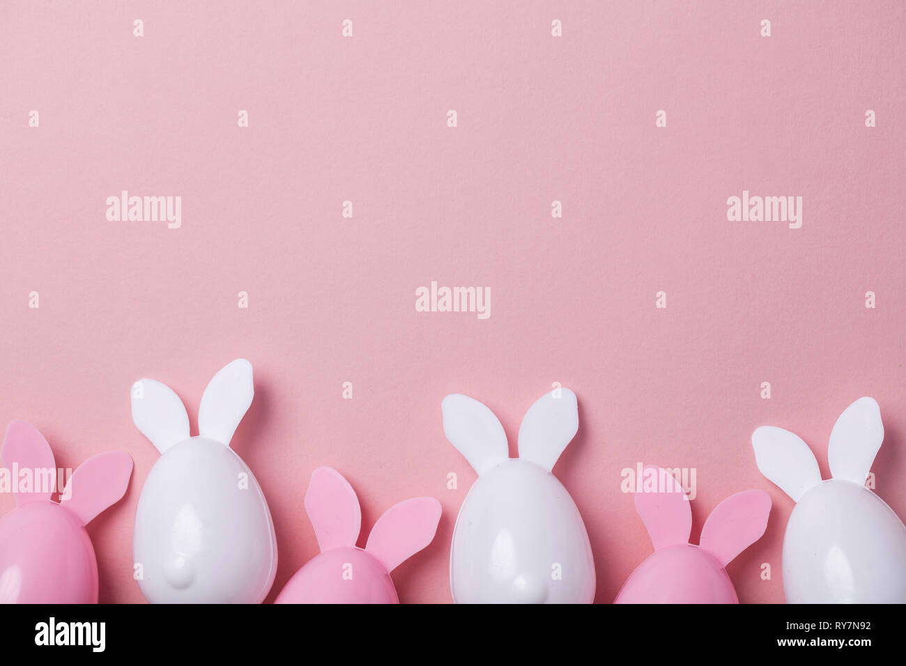 Le uova di pasqua con orecchie di coniglietto su un pastello sfondo rosa Foto Stock