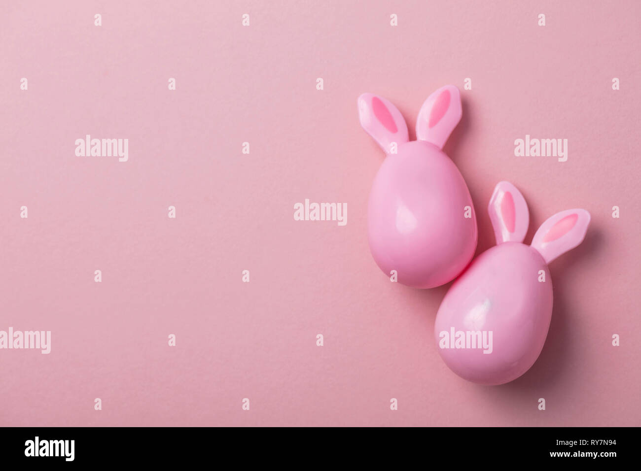 Le uova di pasqua con orecchie di coniglietto su un pastello sfondo rosa Foto Stock