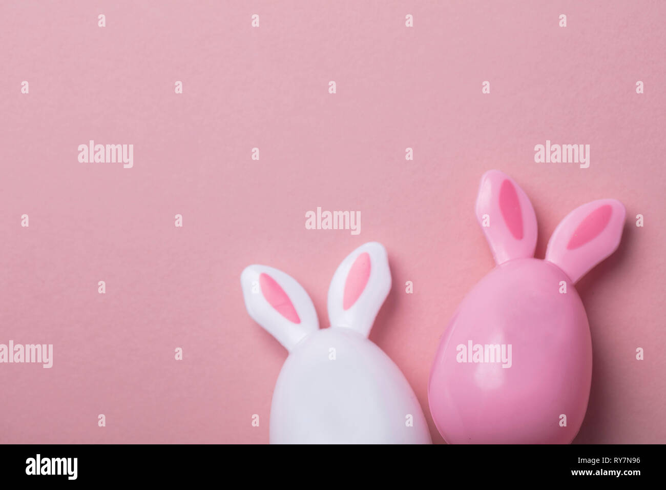 Le uova di pasqua con orecchie di coniglietto su un pastello sfondo rosa Foto Stock
