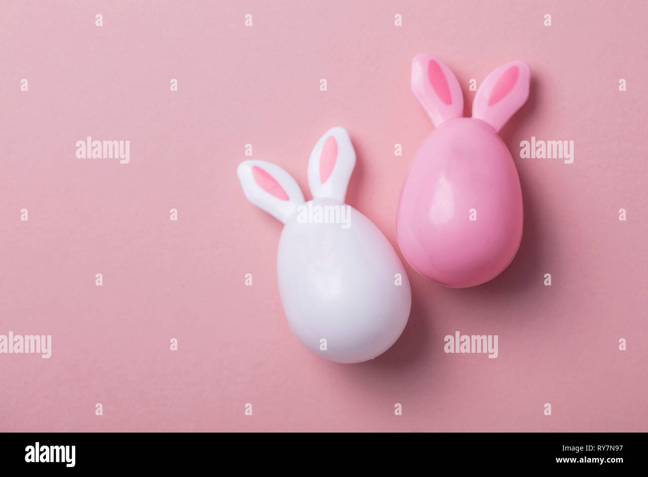 Le uova di pasqua con orecchie di coniglietto su un pastello sfondo rosa Foto Stock