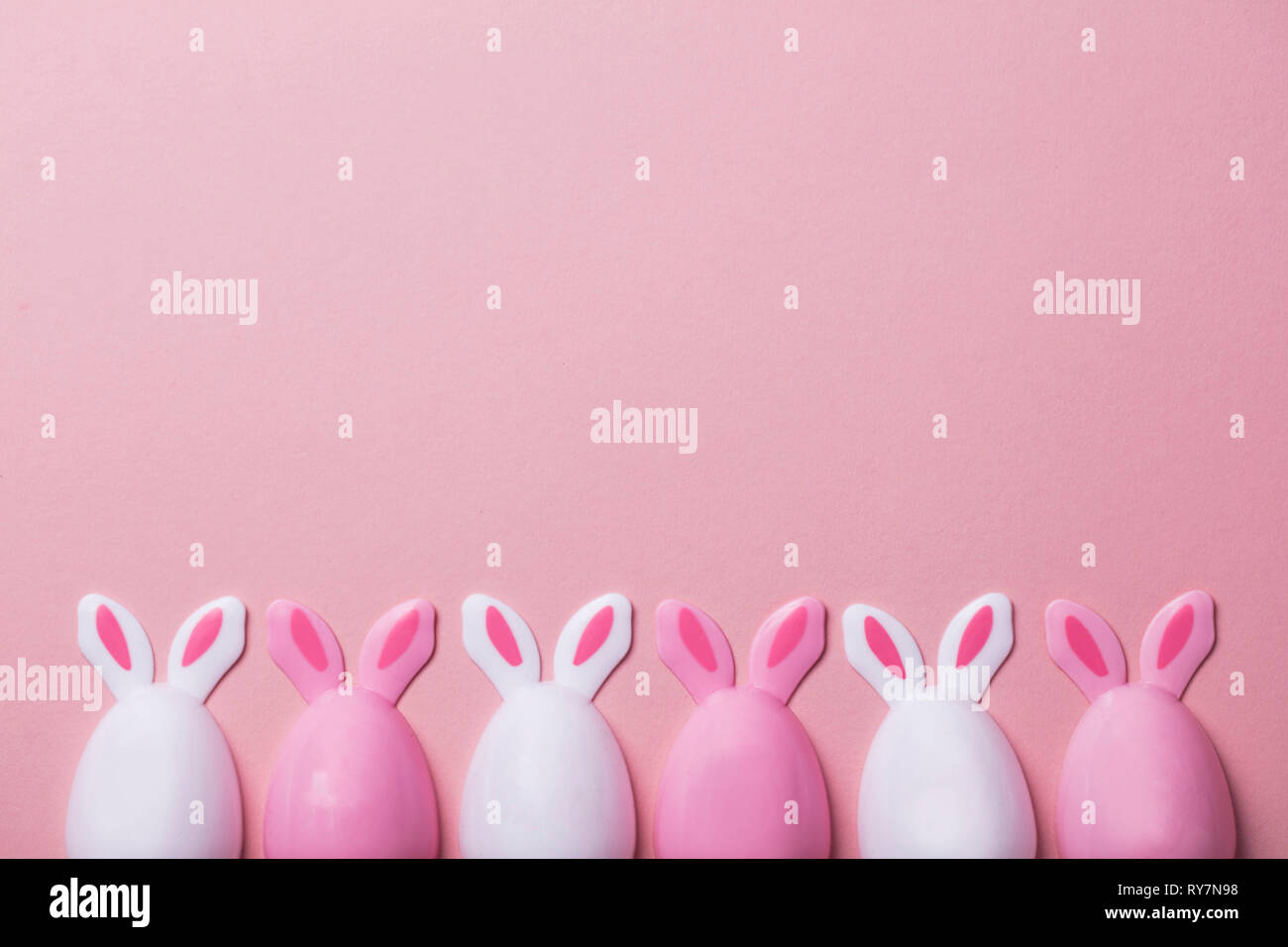 Le uova di pasqua con orecchie di coniglietto su un pastello sfondo rosa Foto Stock