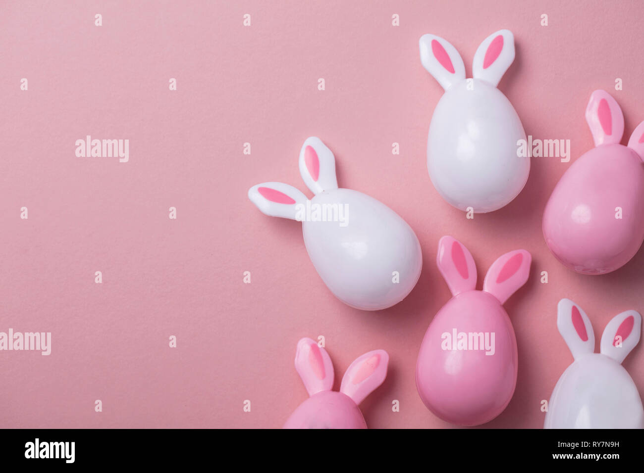 Le uova di pasqua con orecchie di coniglietto su un pastello sfondo rosa Foto Stock