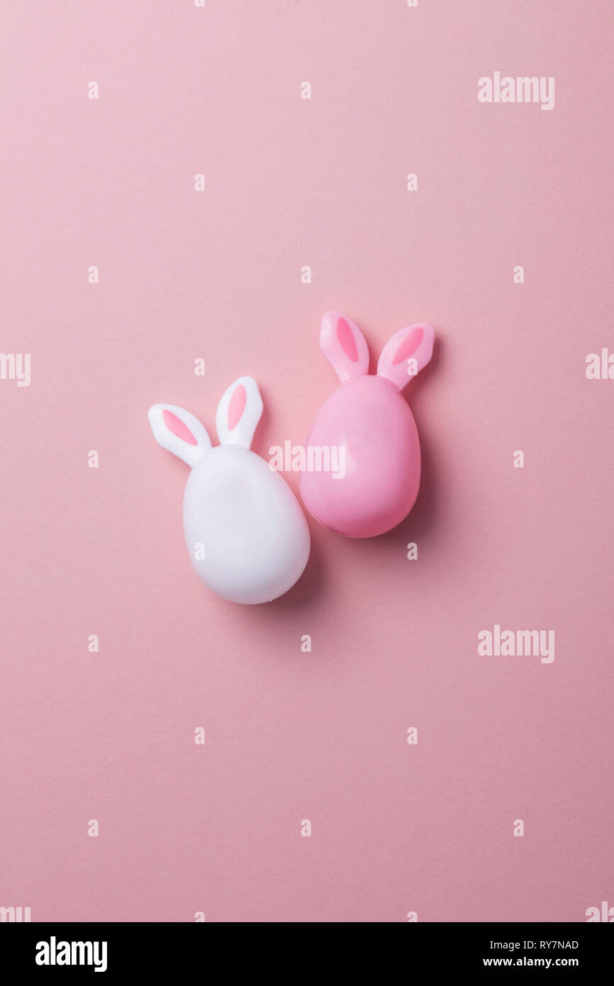 Le uova di pasqua con orecchie di coniglietto su un pastello sfondo rosa Foto Stock