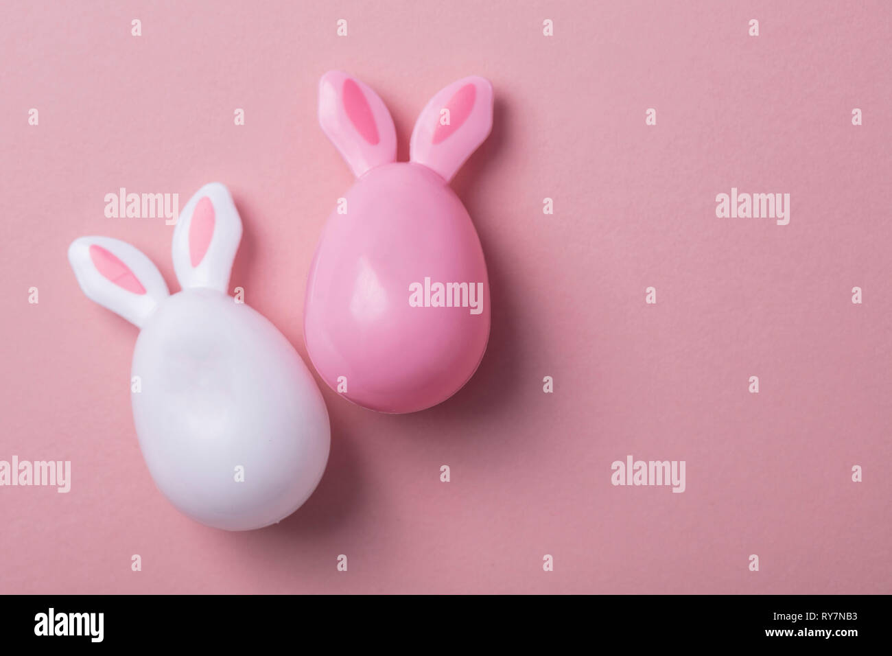 Le uova di pasqua con orecchie di coniglietto su un pastello sfondo rosa Foto Stock