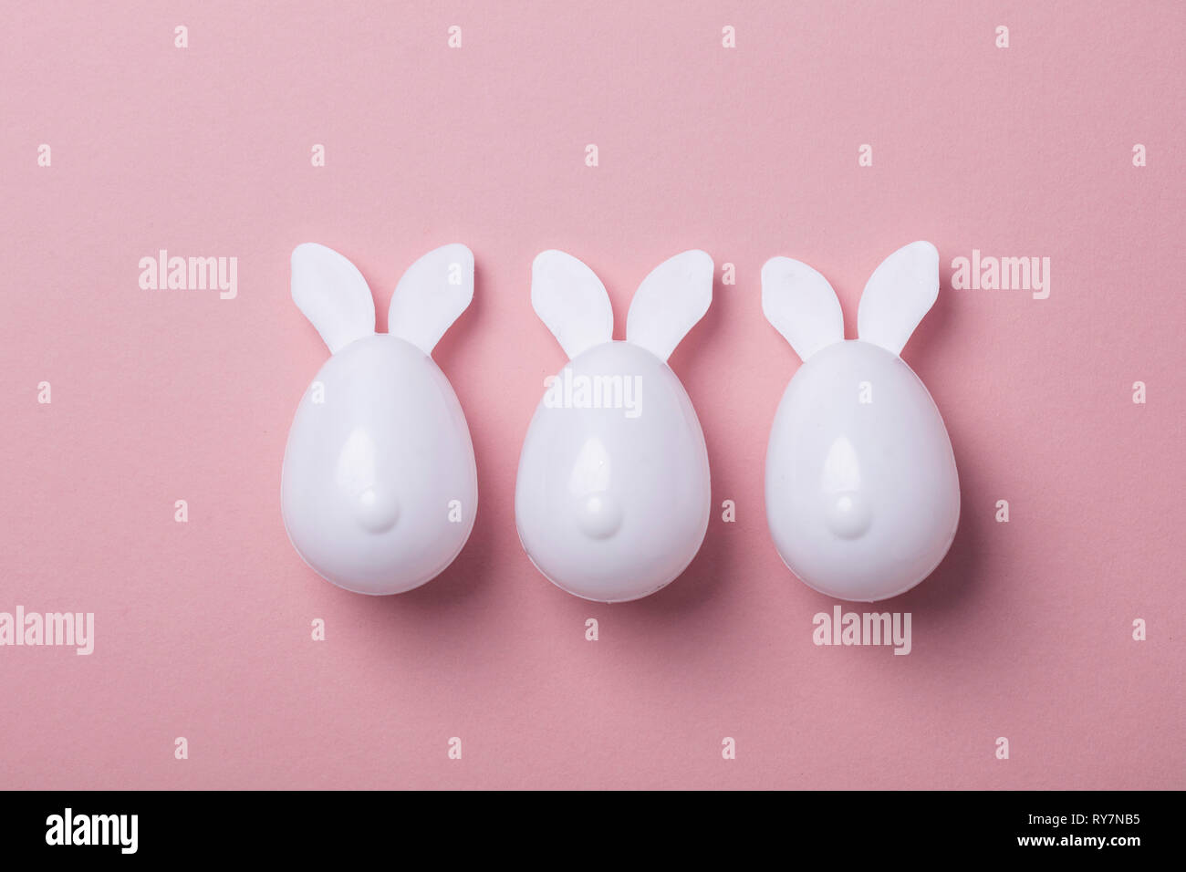 Le uova di pasqua con orecchie di coniglietto su un pastello sfondo rosa Foto Stock