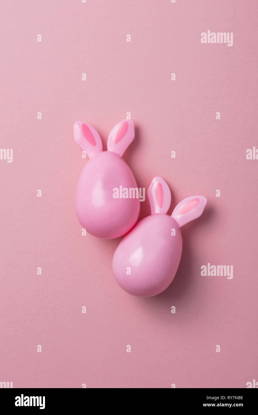 Le uova di pasqua con orecchie di coniglietto su un pastello sfondo rosa Foto Stock