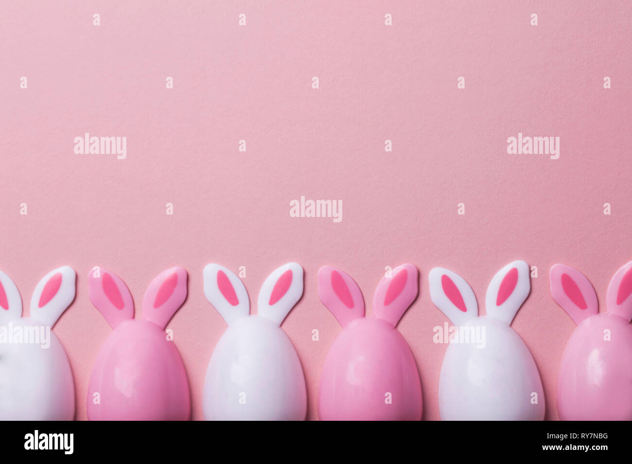 Le uova di pasqua con orecchie di coniglietto su un pastello sfondo rosa Foto Stock