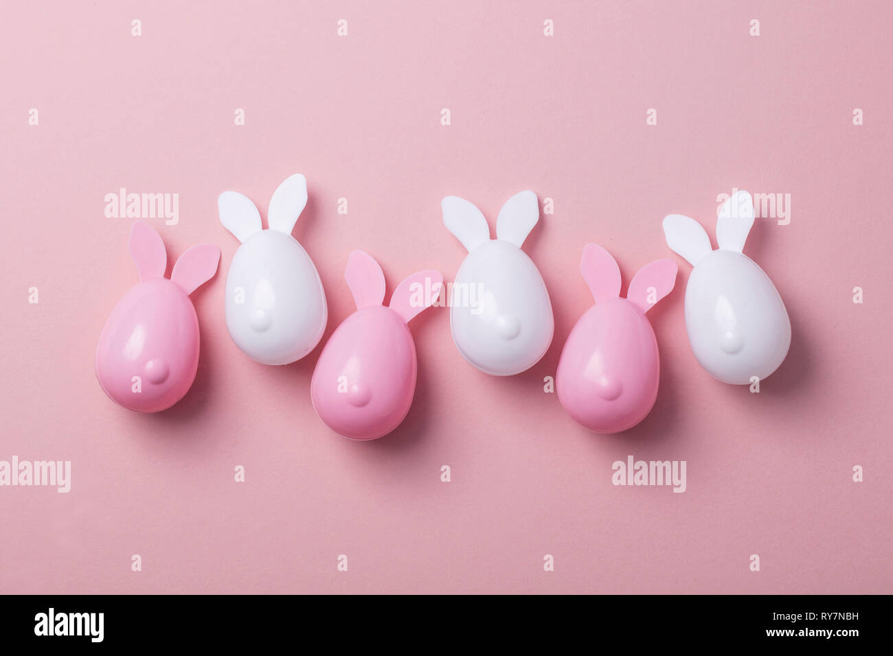 Le uova di pasqua con orecchie di coniglietto su un pastello sfondo rosa Foto Stock