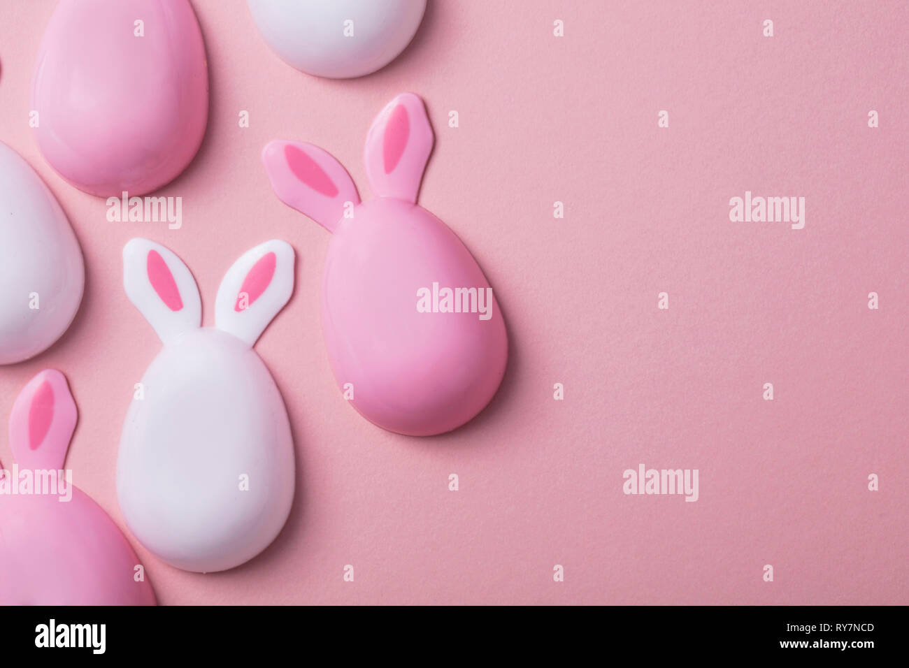 Le uova di pasqua con orecchie di coniglietto su un pastello sfondo rosa Foto Stock