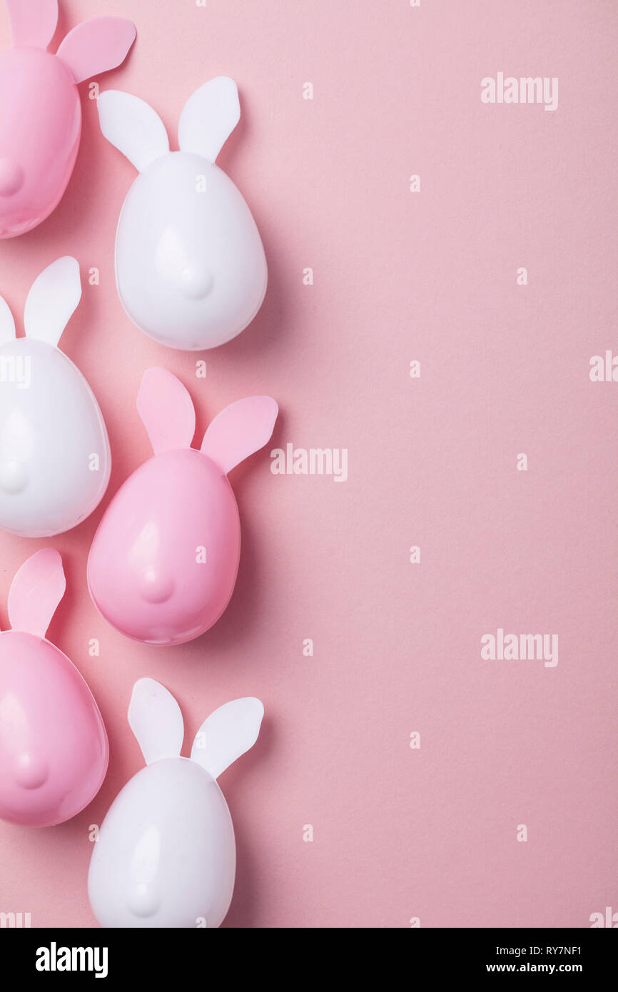 Le uova di pasqua con orecchie di coniglietto su un pastello sfondo rosa Foto Stock
