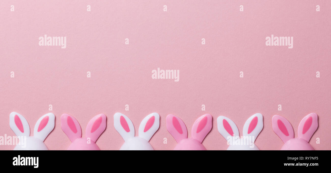 Le uova di pasqua con orecchie di coniglietto su un pastello sfondo rosa Foto Stock