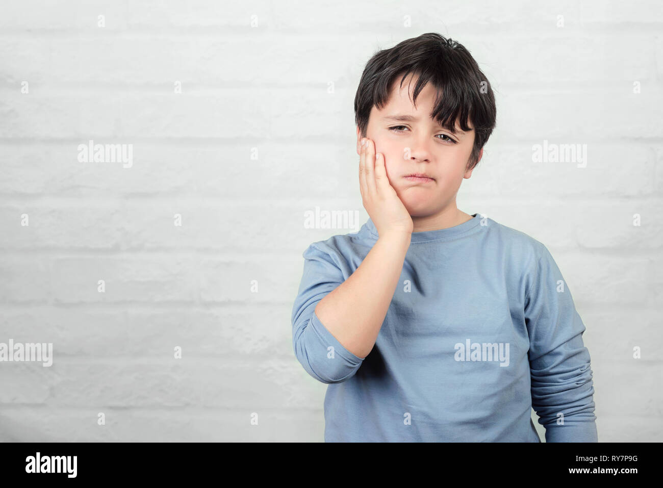 Bambino con il mal di denti contro Sfondo mattone Foto Stock