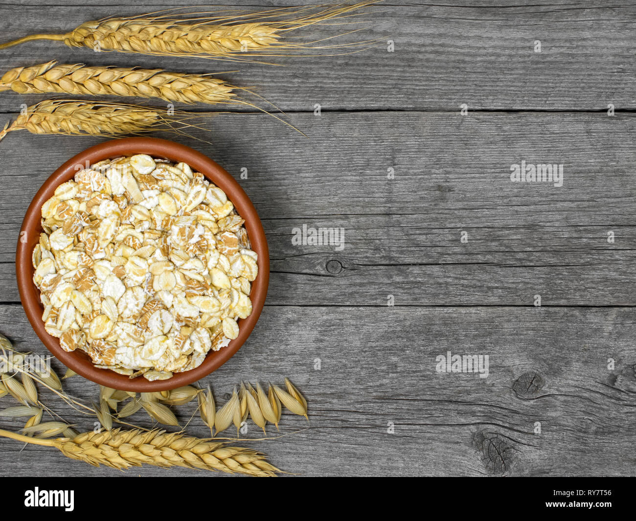 Di fiocchi di cereali in marrone della piastra sulla tabella di schede di grigio. Spikelets di diversi tipi di grano Foto Stock