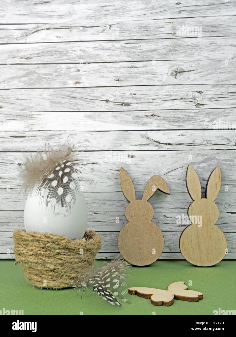 Sfondo di pasqua con uovo di pasqua, conigli pasquali e butterfly isolato sul verde nella parte anteriore del legno Foto Stock