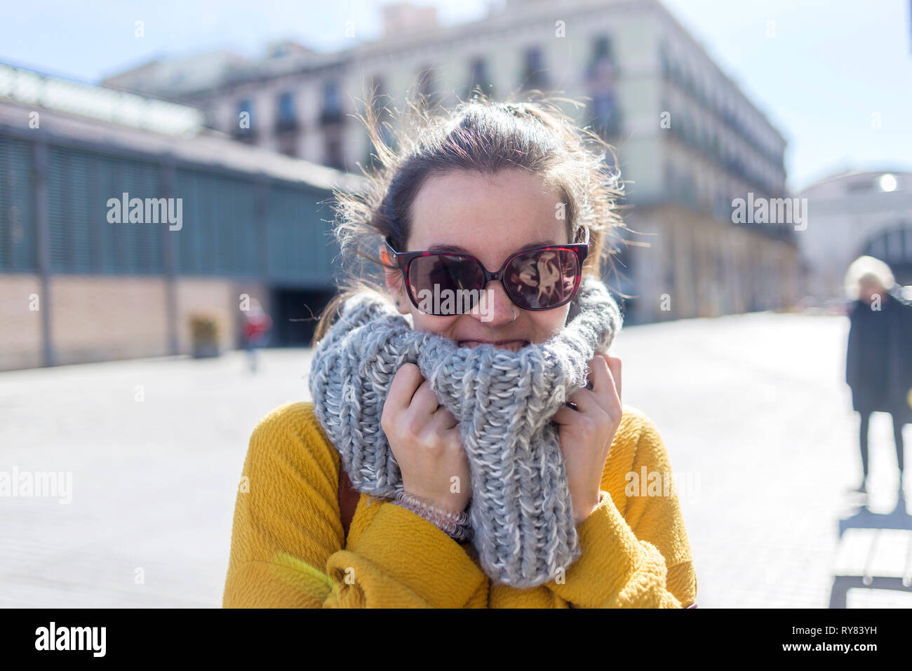 Ritratto di turista femminile di indossare un abbigliamento caldo e occhiali da sole in piedi in città durante la giornata di sole Foto Stock