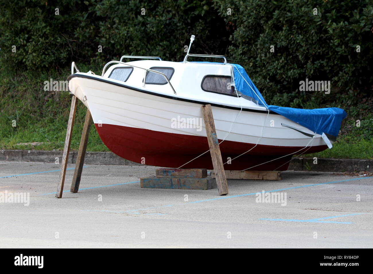 Completamente restaurato piccola barca prese al di fuori dell'acqua durante il periodo invernale sul locale parcheggio supportati con travi in legno e coperto con protezione in nylon Foto Stock