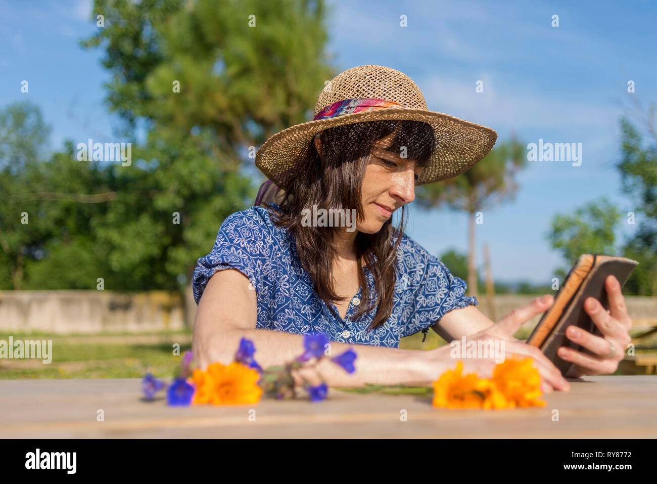Donna matura indossando hat utilizzando la tabella computer presso la fattoria durante la giornata di sole Foto Stock