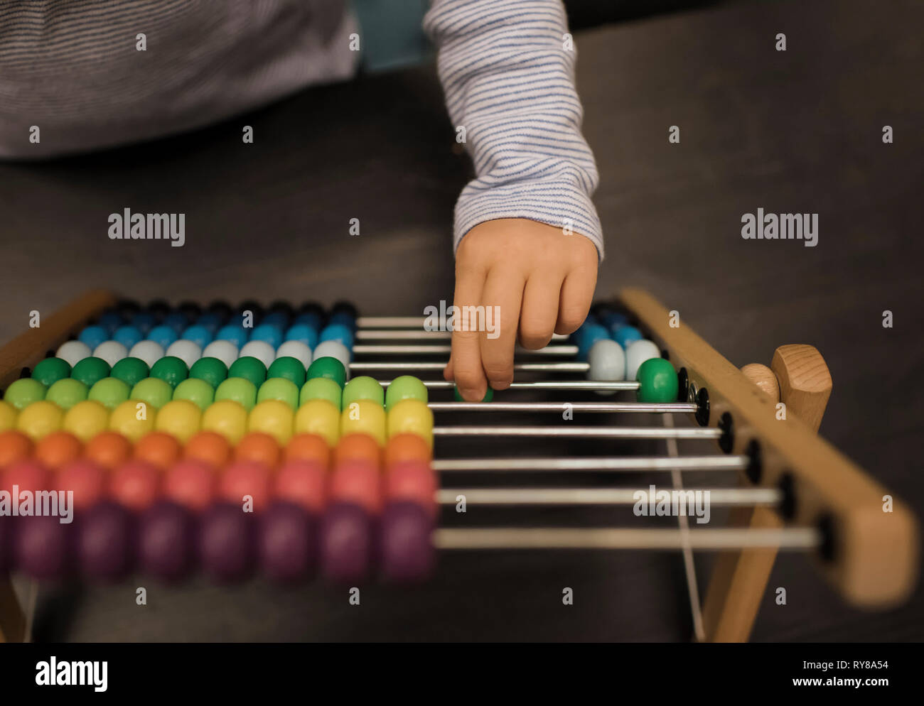 Ritagliate la mano della ragazza utilizzando abacus sulla tavola a casa Foto Stock