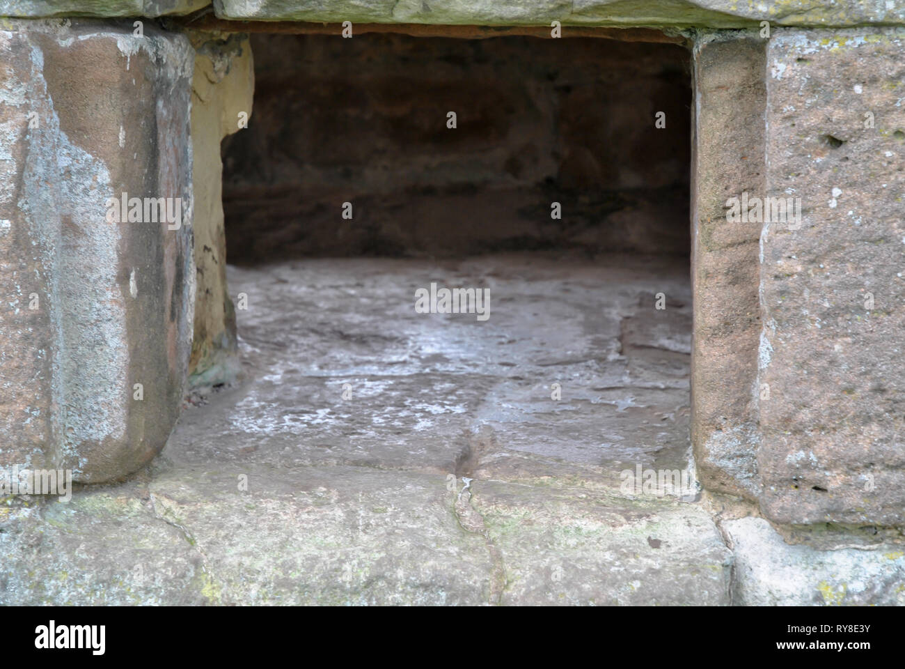 Un foro rettangolare in un antico muro di pietra Foto Stock