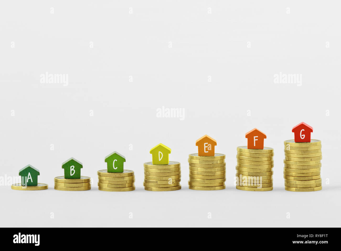 Case in miniatura con efficienza energetica di etichette su pile di coin - Concetto di edilizia Energia nominale Foto Stock