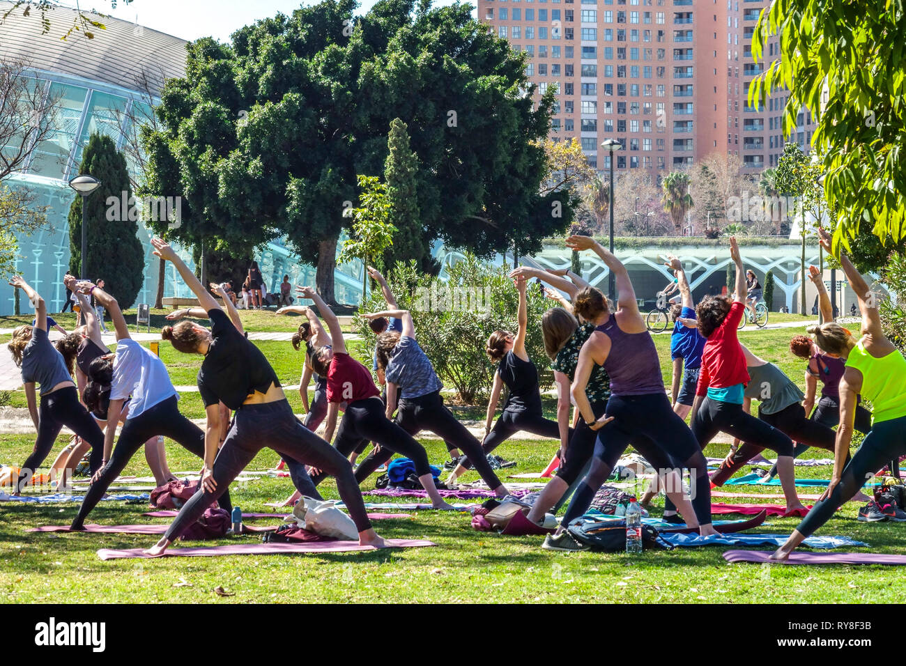 Nel Parco Turia di Valencia, la gente si incontra nel giardino e pratica yoga gruppo classe Valencia Spagna parco della città folla sano stile di vita giardino yoga Foto Stock