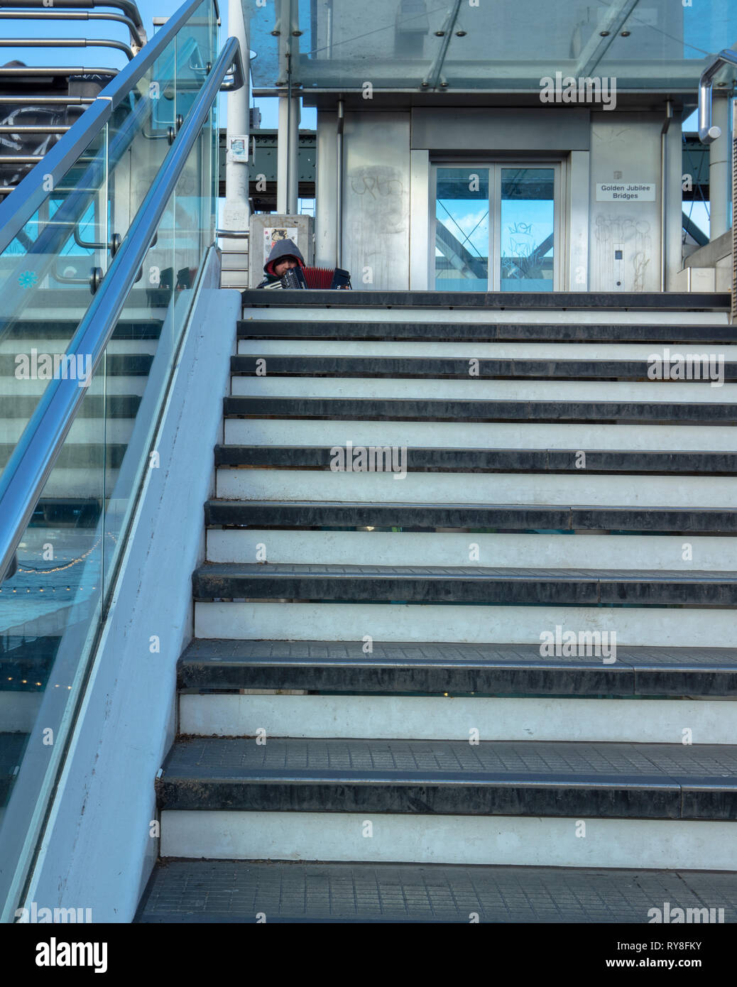 Maschio lettore di fisarmonica intrattiene i turisti in occasione del Giubileo d oro ponte di South Bank di Londra, Regno Unito su una ventilata, freddo ma soleggiato nel pomeriggio in marzo. Foto Stock