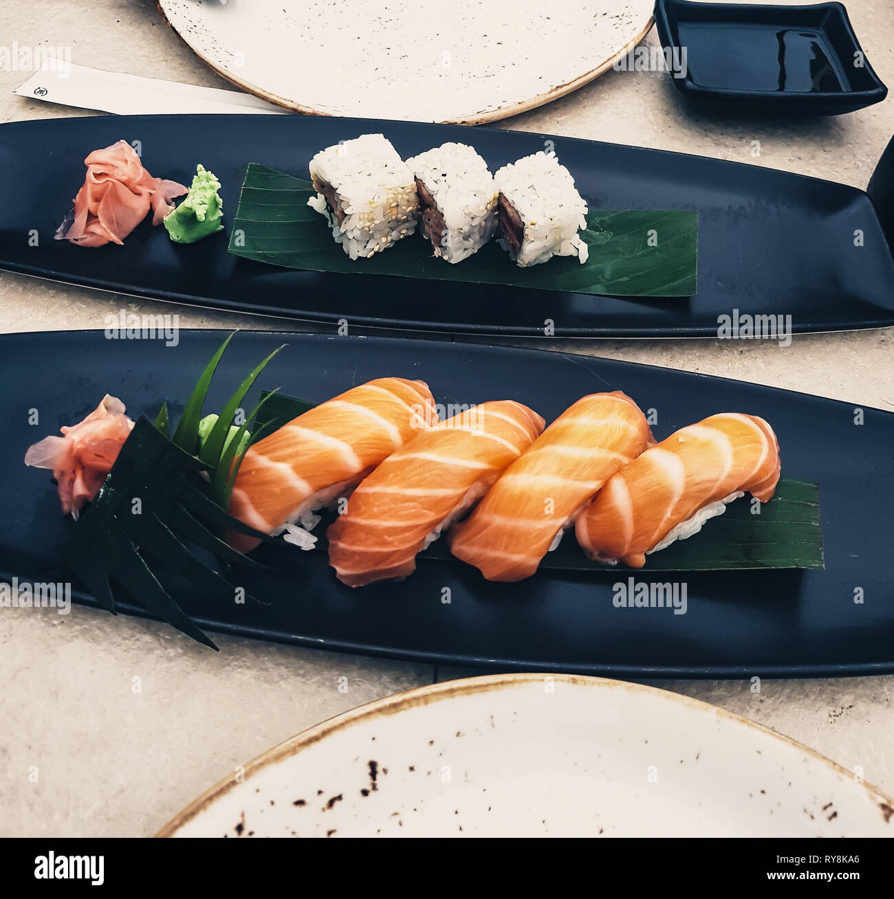 Piatti di sushi di salmone, nigiri e uramaki in un ristorante. Cucina Giapponese con salsa di soia e wasabi - pesce crudo Foto Stock