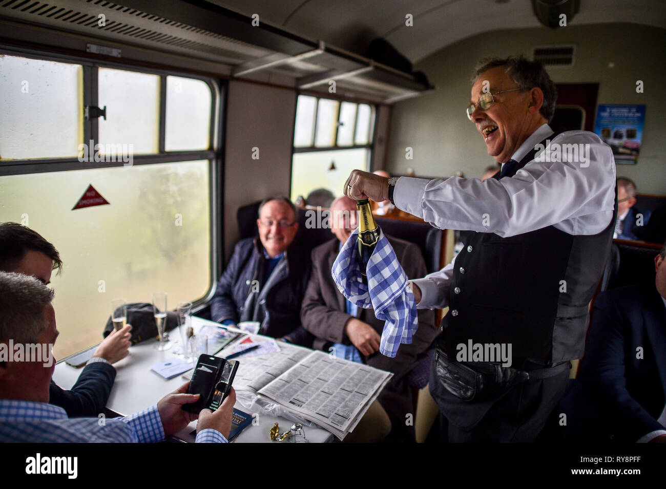 La voce di persone per le gare a Cheltenham sono servito champagne in un periodo di trasporto sulla Gloucestershire Warwickshire ferrovie a vapore da Toddington, dove un patrimonio speciale di vapore treno express service sta prendendo i frequentatori di gara per Cheltenham. Foto Stock