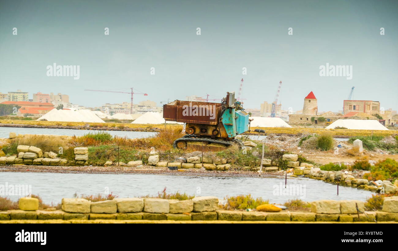 Un vecchio macchinario sulla diga del campo di Trapani e la vista del mucchio di sali di bianco sul retro in Italia Foto Stock