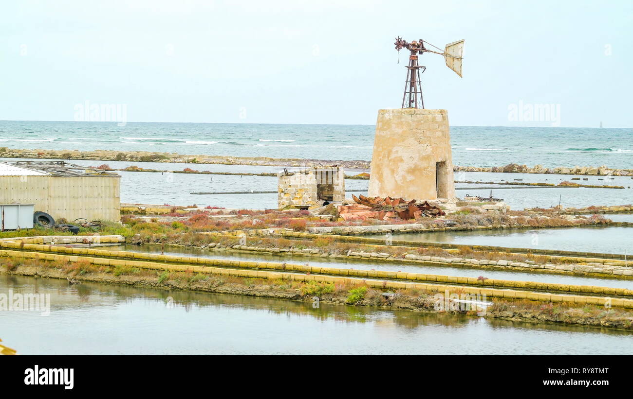Le dighe del campo di saltmine in Trapani in Sicilia e la vecchia banderuola segnavento in medio in Italia Foto Stock